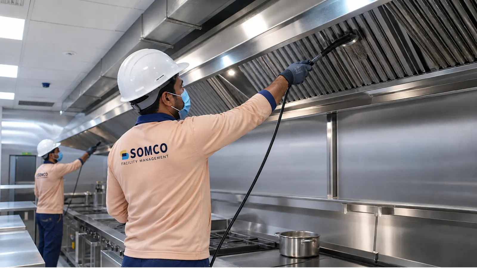Technicians cleaning stainless steel commercial kitchen exhaust hood filters