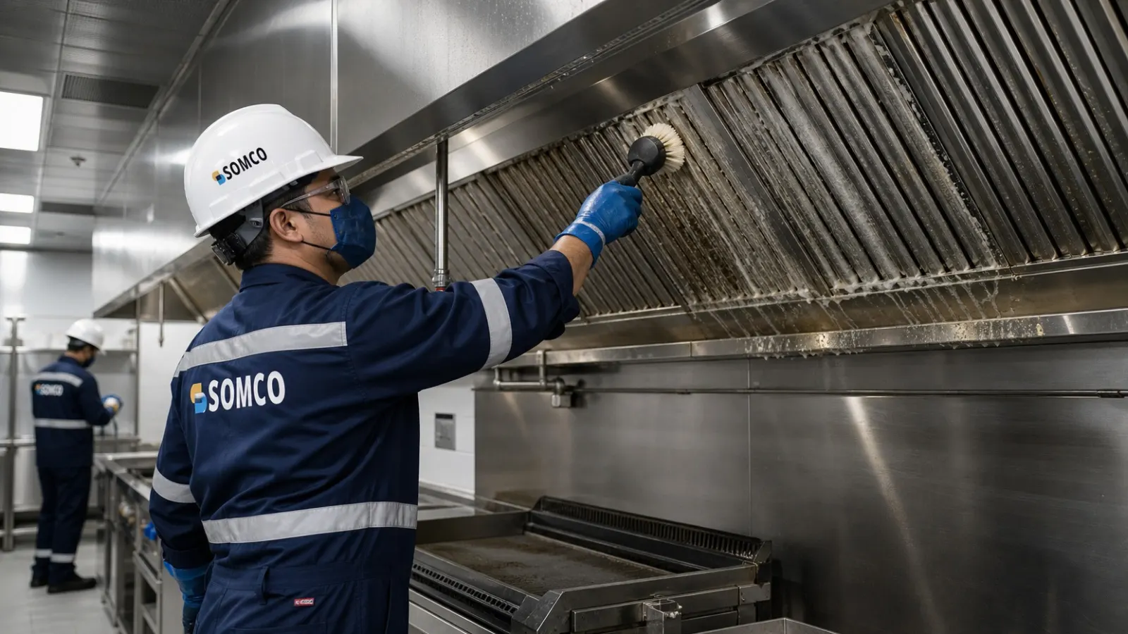 Professional technician cleaning a commercial kitchen exhaust hood and grease filters.
